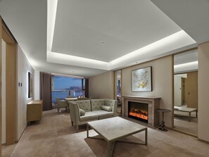 A modern living room with a fireplace, a sofa, a coffee table, and a view of a cityscape through large windows.