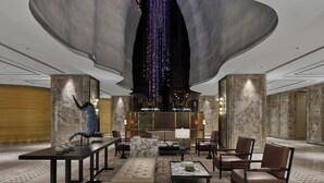 A spacious lobby with a large central sculpture, seating arrangements, and a modern ceiling design.