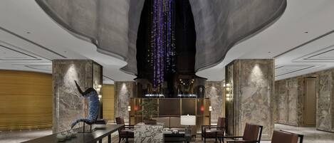 A spacious lobby with a large central sculpture, seating arrangements, and a modern ceiling design.