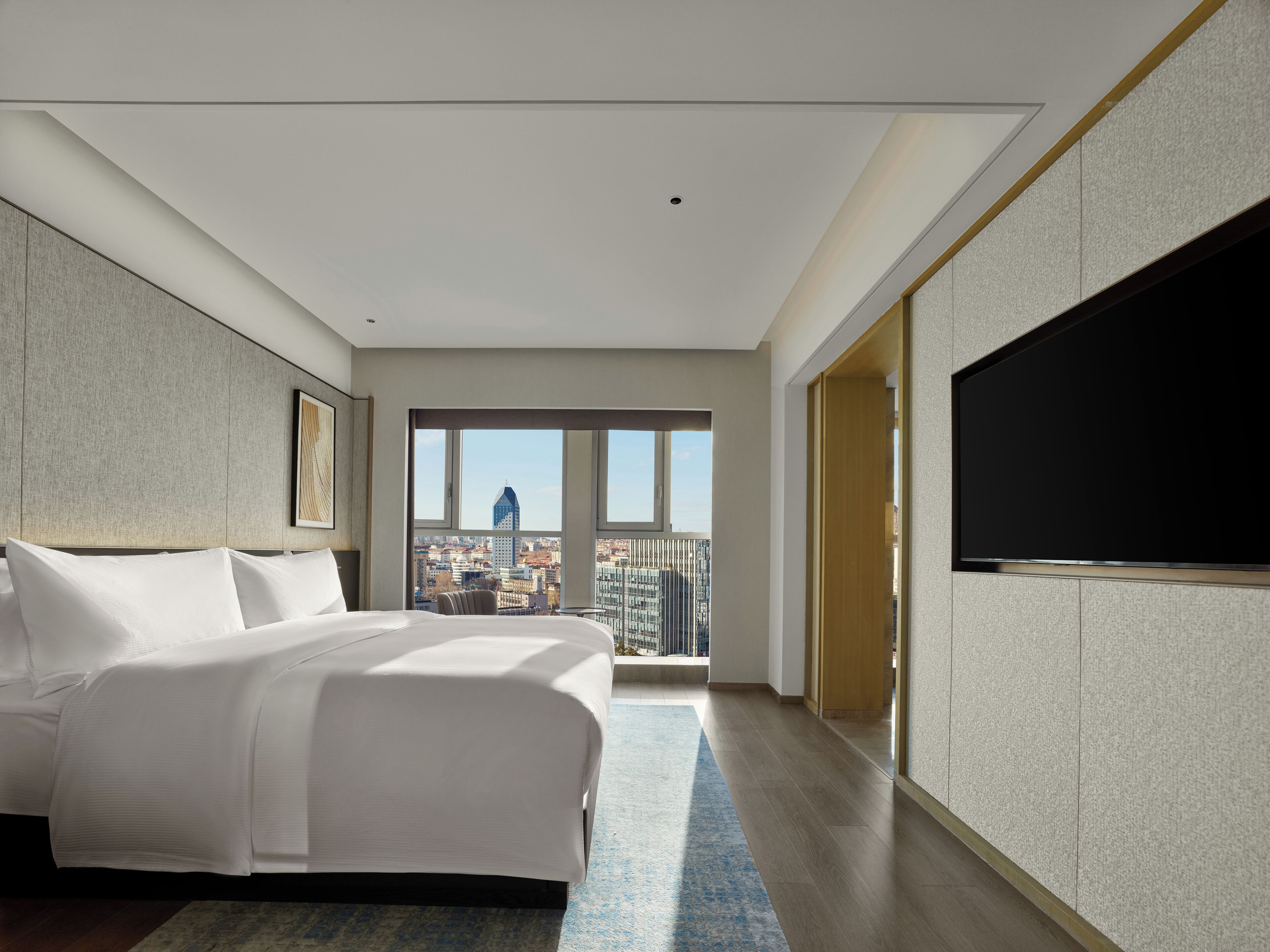 Habitación de hotel moderna con una cama grande, un televisor de pantalla plana y vistas a la ciudad.