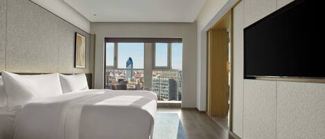Habitación de hotel moderna con una cama grande, un televisor de pantalla plana y vistas a la ciudad.
