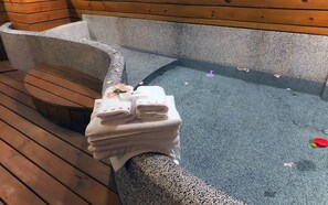 Een houten bank en een stenen hottub met handdoeken erop.