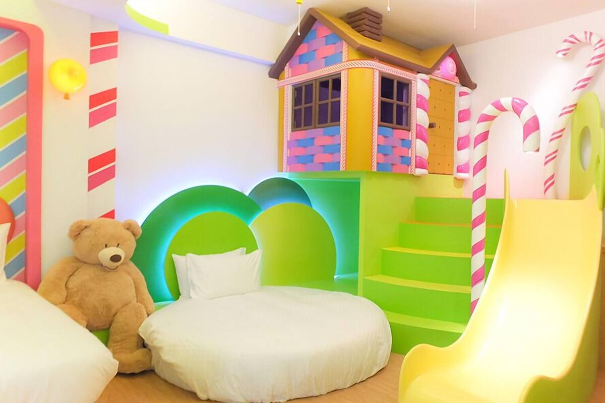 Une salle de jeux pour enfants avec un ours en peluche, un toboggan et des structures de jeu colorées.