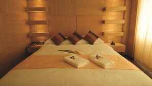 A hotel room with a large bed, wooden headboard, bedside tables, and a window with curtains. - Westerngrand Hotel Ratchaburi (Ratchaburi)