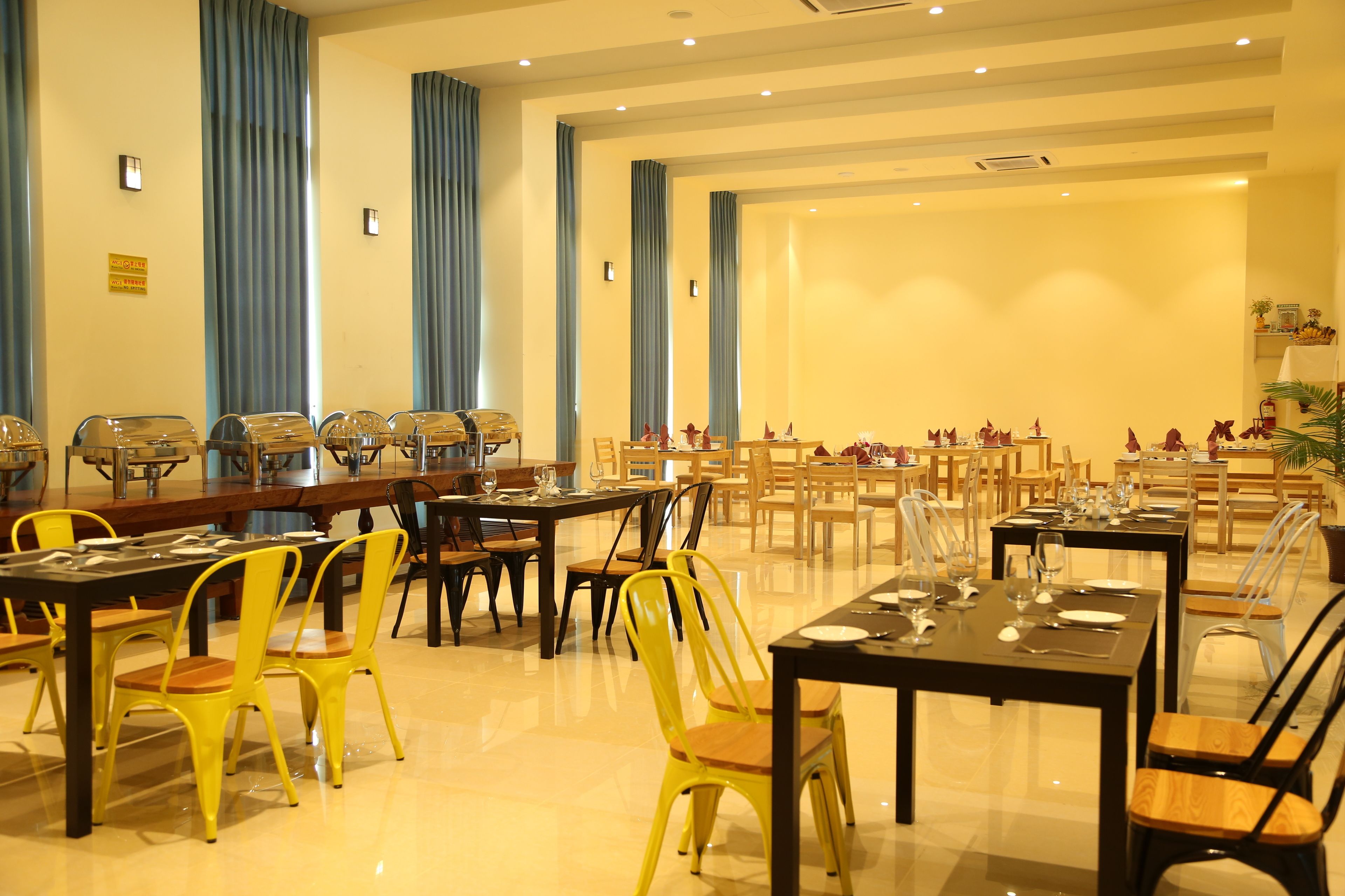 Un salón de conferencias con varias mesas y sillas, dispuesto para reuniones o eventos.