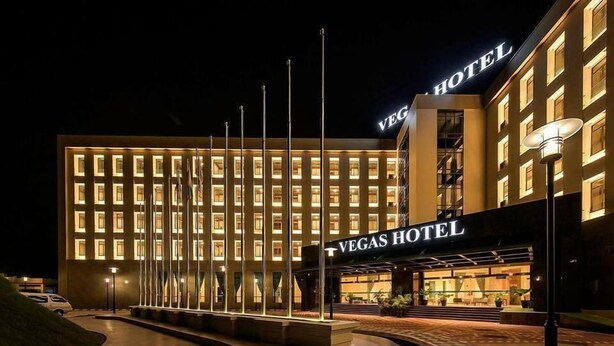 L’extérieur de l’hôtel Vegas se distingue par sa façade bien éclairée, son entrée imposante et une série de mâts porte-drapeaux.