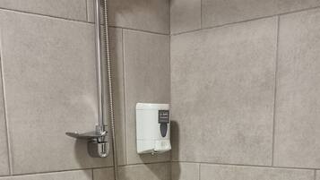 Een badkamer met een bad, een handdouche en een bedieningspaneel aan de muur.