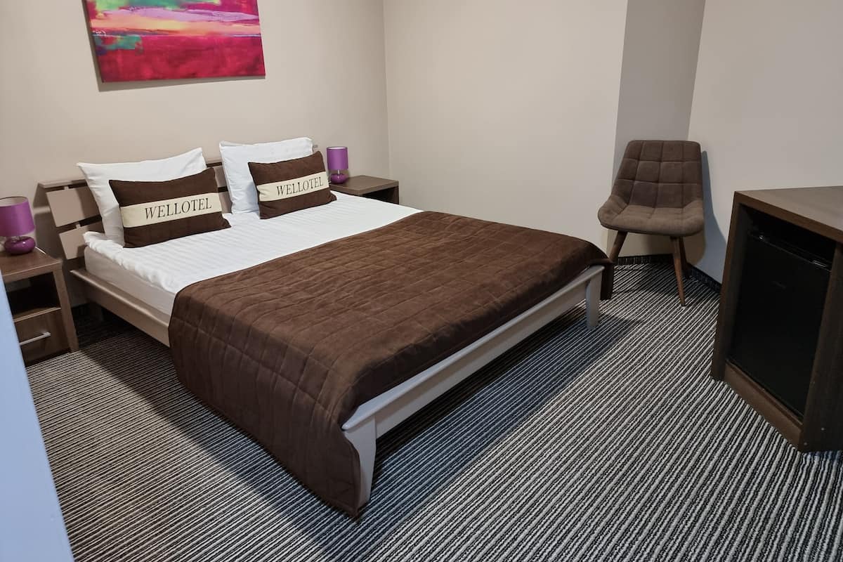 Ein Hotelzimmer mit einem Bett, einem Sessel, einem Fernseher und einem Bild an der Wand.