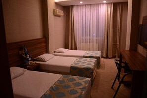 A hotel room with two single beds, a wooden headboard, a desk with a chair, and a large window with curtains. - Ayintap Hotel (Gaziantep)
