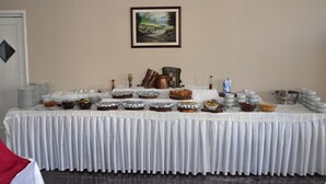 A buffet table with various food items and condiments, set against a plain wall with a painting above. - Ayintap Hotel (Gaziantep)