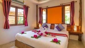 Habitación de hotel con cama, cortinas, unidad de aire acondicionado y ventana con vistas a zonas verdes.
