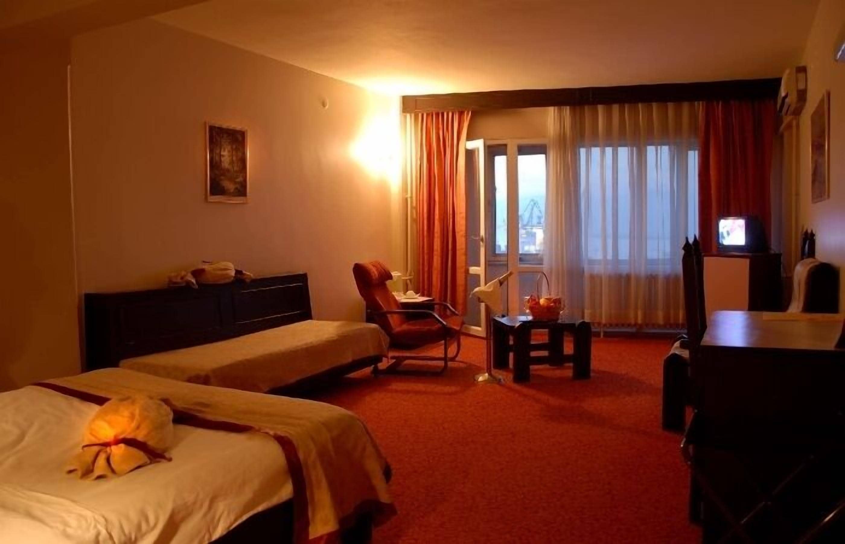 Une chambre d’hôtel avec deux lits, un bureau, une chaise, une télévision et une vue sur l’extérieur.