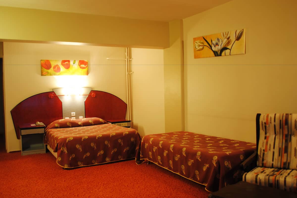 Une chambre d’hôtel avec deux lits, une table de chevet, une chaise et un tableau au mur.