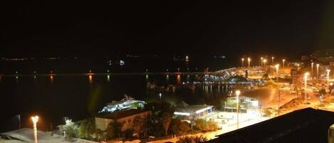 A nighttime view of a waterfront area with buildings, streetlights, and a dock.