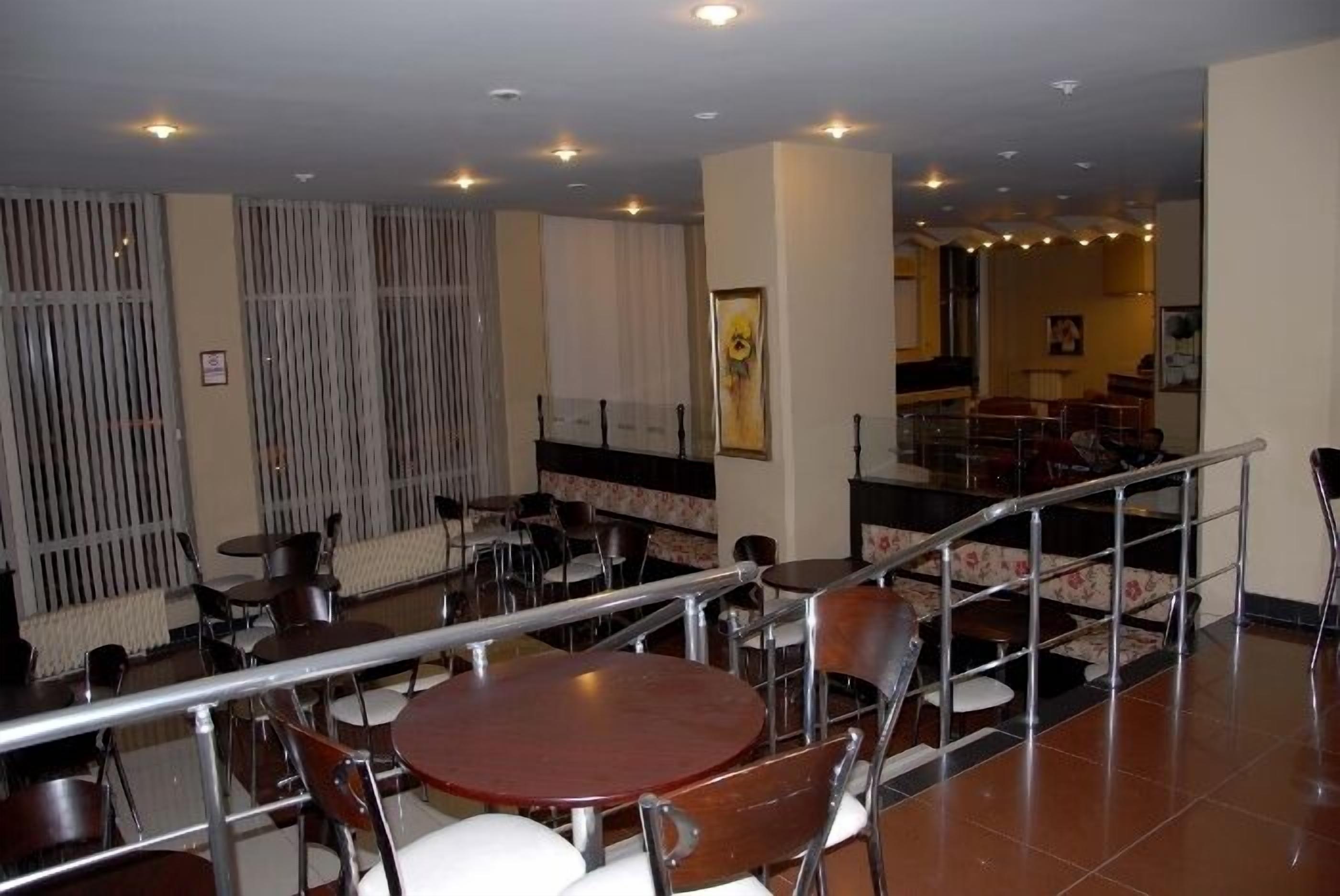A dining area with round tables and chairs, a staircase, and a view of the restaurant area.