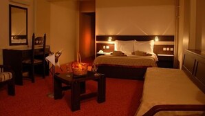 Una habitación de hotel con una cama, una mesita de noche con una cesta de fruta, una silla y un escritorio.