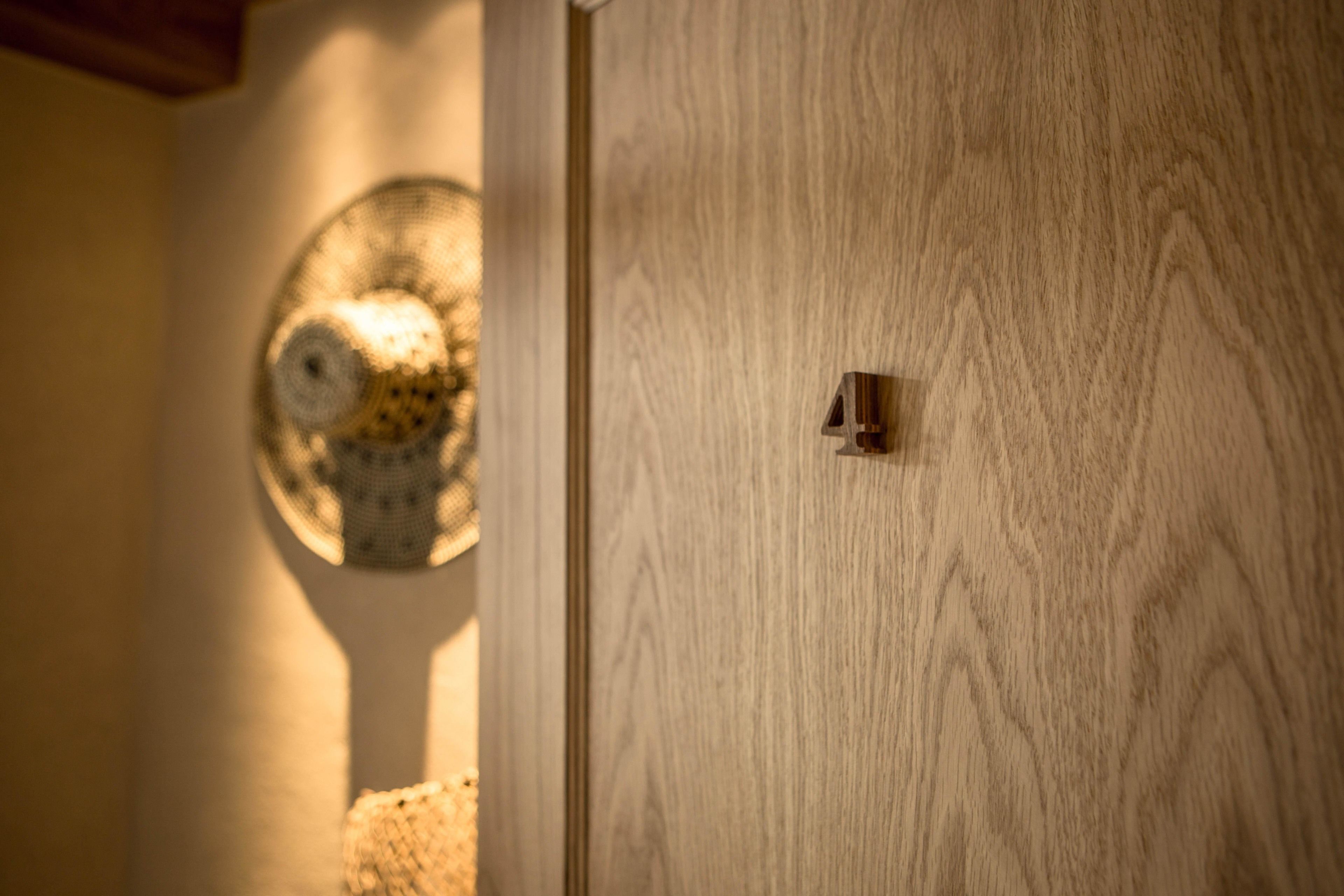 A wooden door with a brass handle and a circular window with a patterned design.