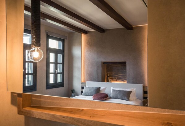 A bedroom with a bed, a nightstand, a window, and a fireplace.