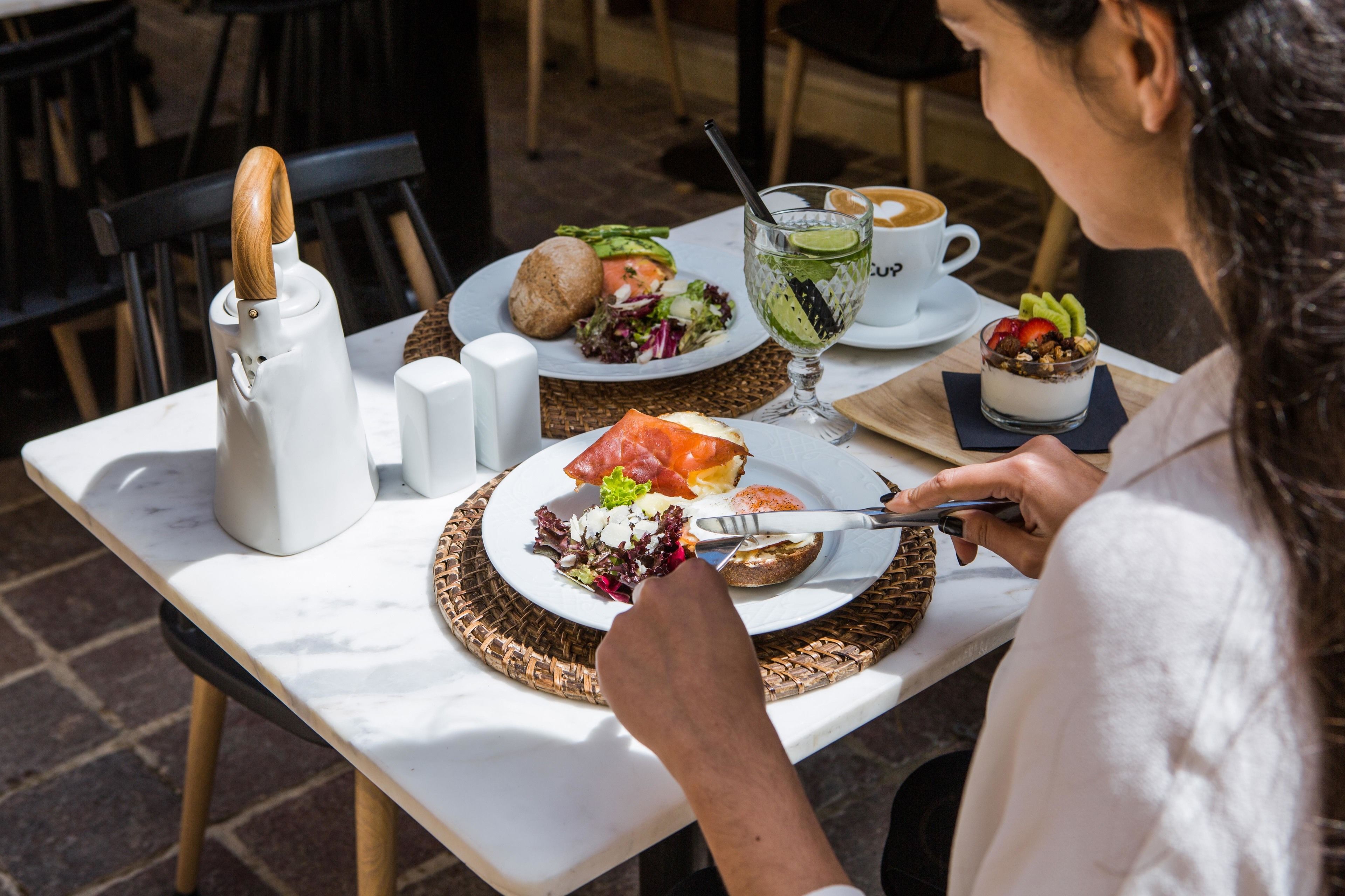 A dining table with a plate of food, a cup of coffee, and a glass of water.