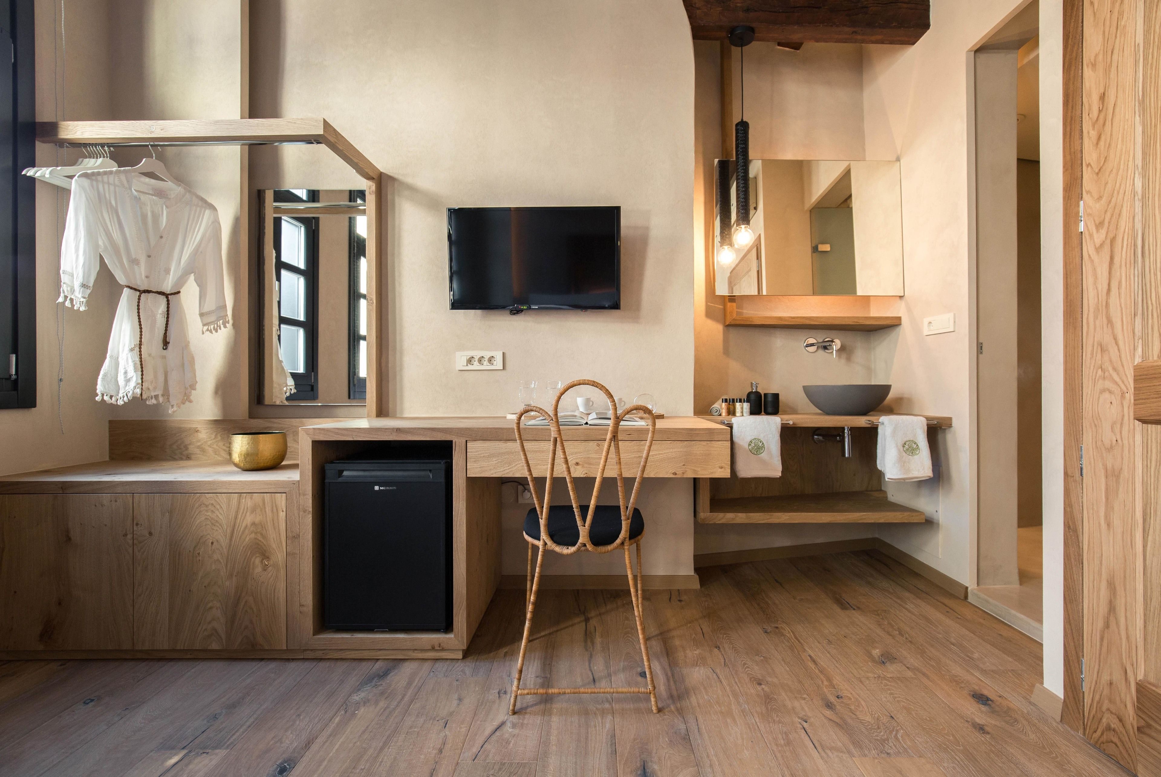 Una cocina moderna con encimera de madera, lavavajillas integrado, una silla de mimbre, televisor de pantalla plana y un espejo grande sobre el lavabo.