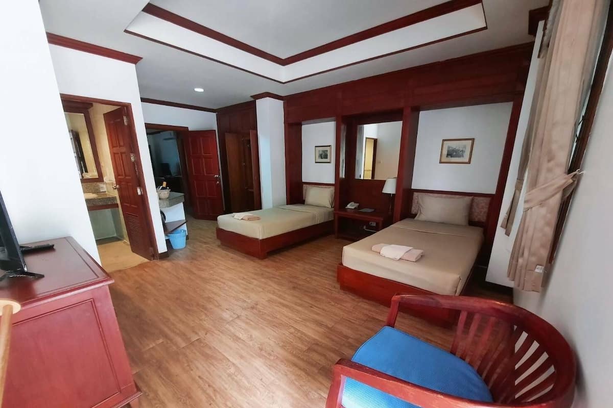 Una habitación de hotel con suelo de madera, dos camas, un escritorio y una silla.
