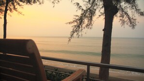 A wooden bench overlooking a beach with a view of the ocean and trees. - The Princess Beach Resort (Klaeng)