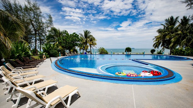 A pool area with lounge chairs and a view of the ocean. - The Princess Beach Resort (Klaeng)