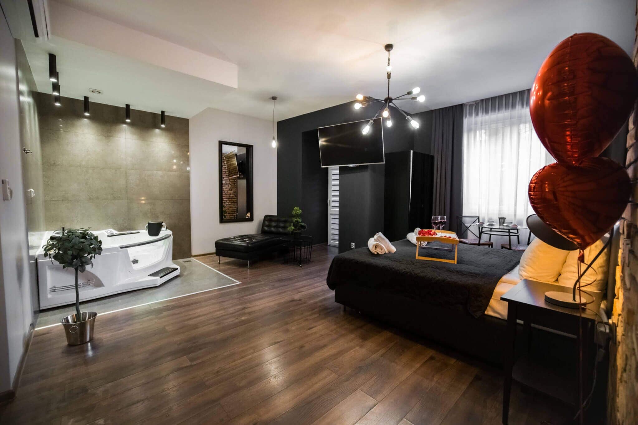Una sala de estar moderna con un sofá negro, una zona de comedor y un televisor grande.