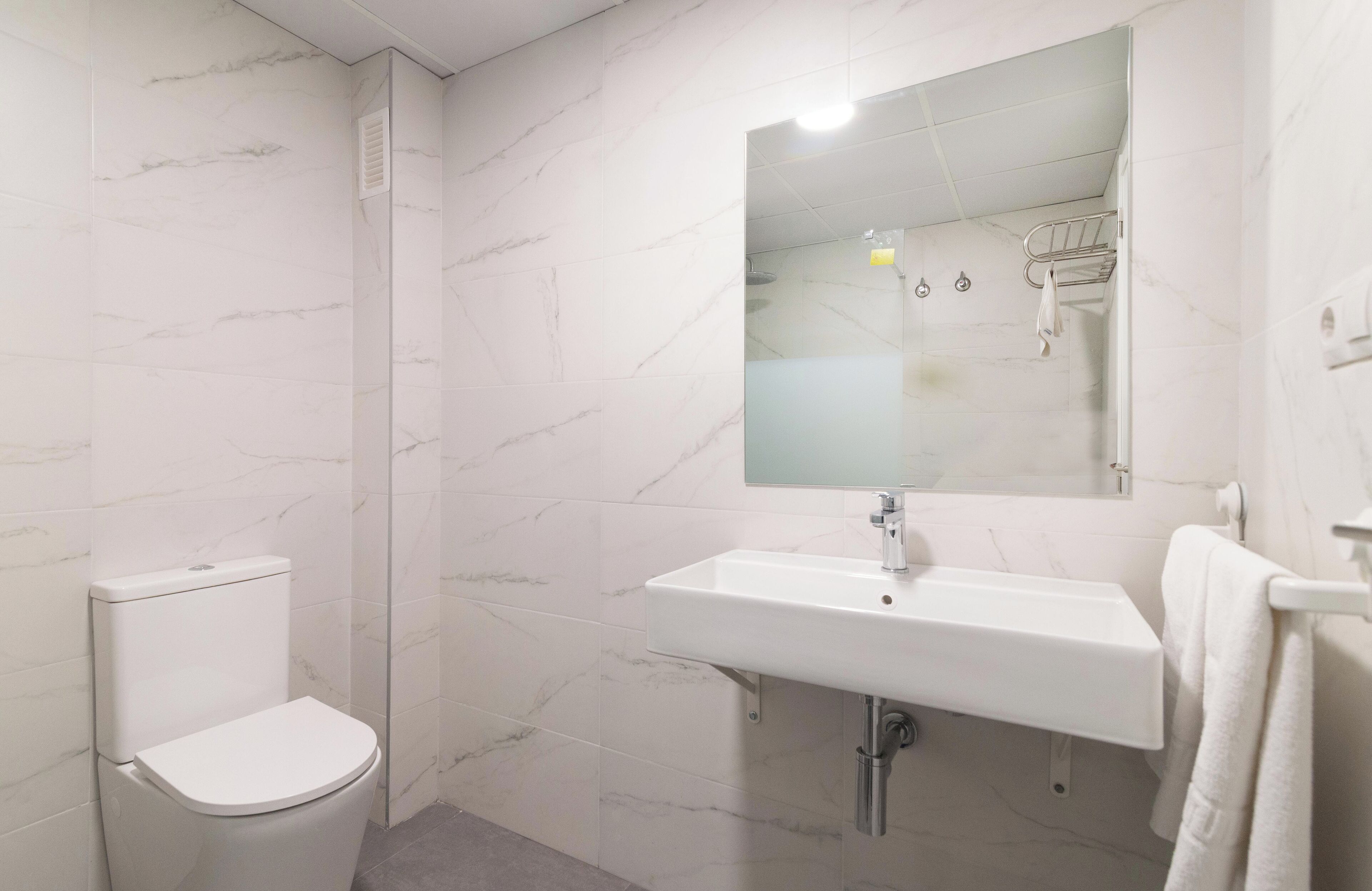 A bathroom with a toilet, sink, and mirror.
