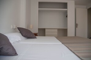 A bedroom with a bed, a nightstand, a wardrobe, and a door. - Apartamentos Maja (Benidorm)