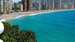 A coastal cityscape with high-rise buildings, a beach with sunbathers, and clear blue waters. - Apartamentos Maja (Benidorm)