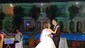 Una recepción de boda con una larga mesa dispuesta para los invitados, una botella de agua y un centro de mesa floral.