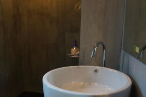 Un baño con lavamanos blanco, un espejo y un perchero para toallas.