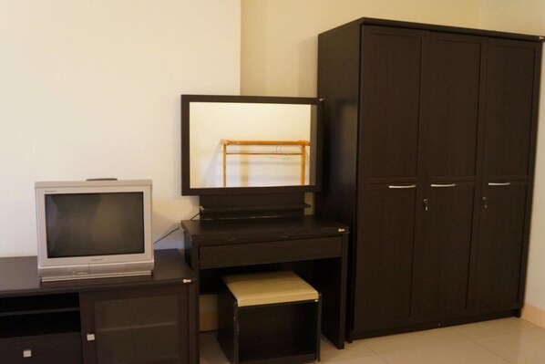 Una habitación con un escritorio de madera oscura, un televisor y un armario.