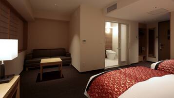 Ein Hotelzimmer mit zwei Betten, einem Sofa, einem Tisch und einer Lampe.