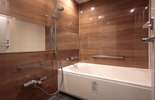 Un baño moderno con una bañera blanca grande, cabina de ducha con mampara de vidrio y paneles de madera en las paredes.