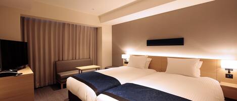 Habitación de hotel con una cama grande, televisión, escritorio y una silla.