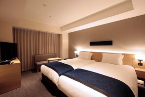 Ein Hotelzimmer mit einem großen Bett, einem Fernseher, einem Schreibtisch und einem Stuhl.