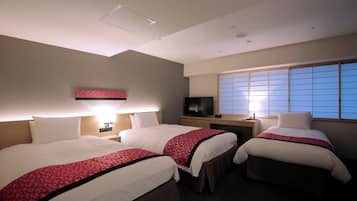 Habitación de hotel con dos camas, un televisor, una ventana con persianas y una mesita de noche con lámpara.