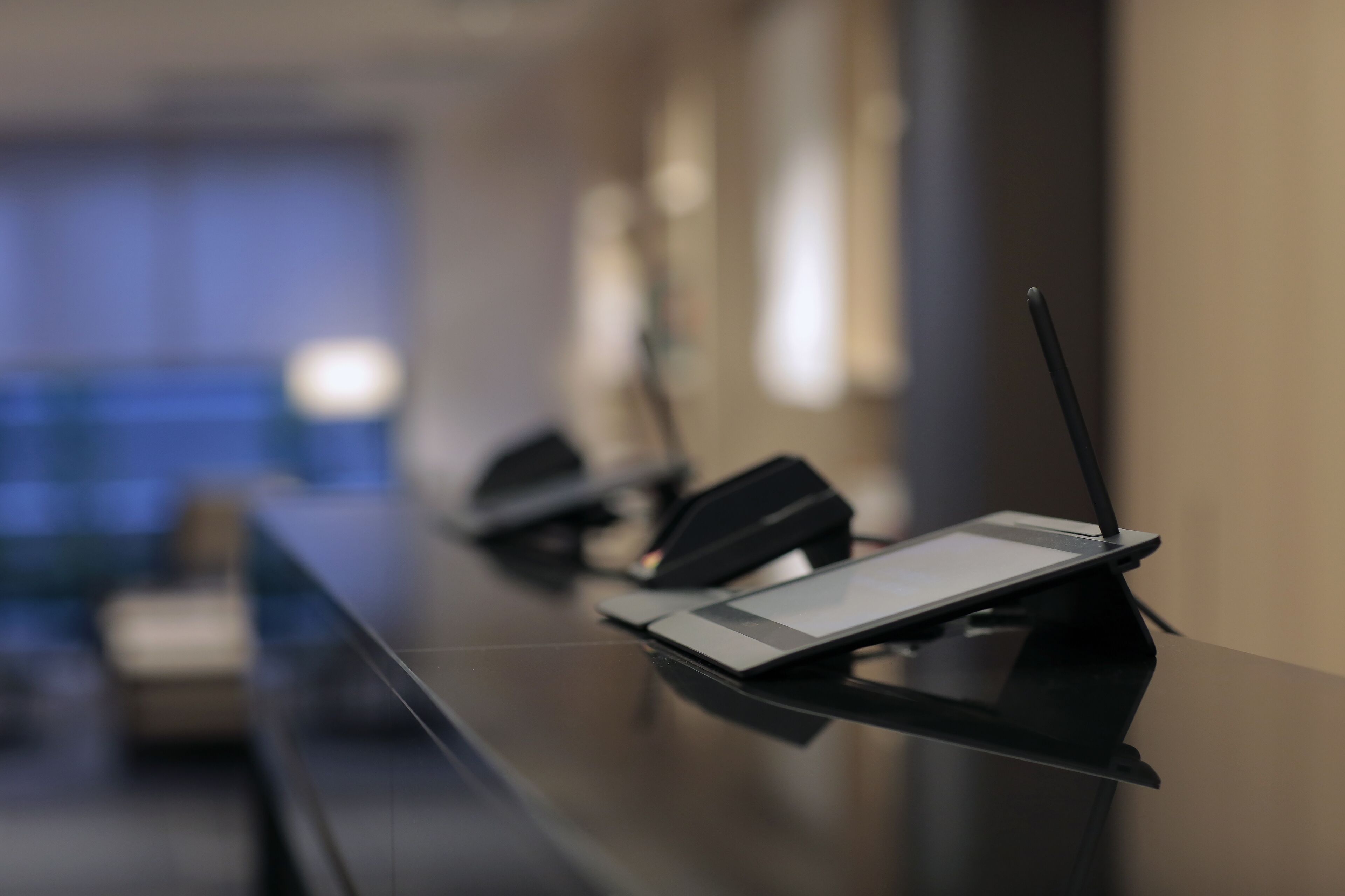 Una mesa de conferencias con un ordenador portátil y un teléfono inteligente sobre un soporte.