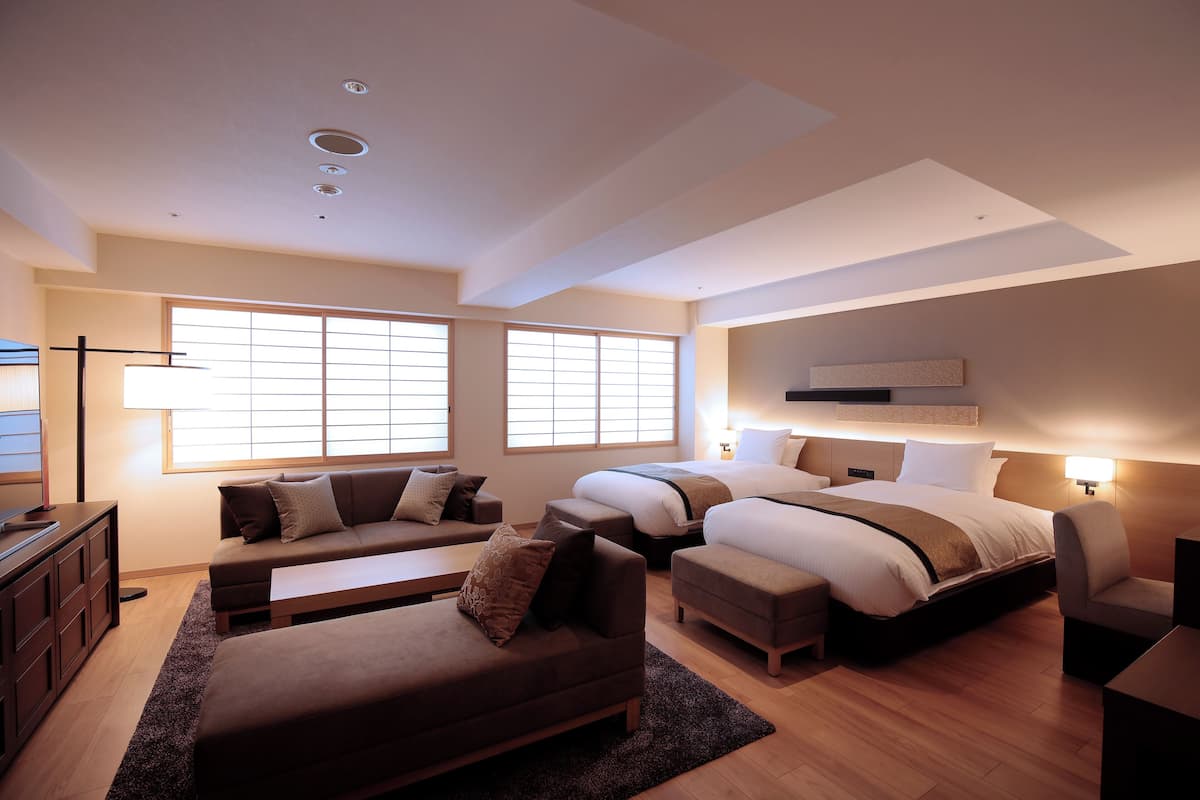 Una habitación de hotel moderna con una cama grande, un sofá, un escritorio y un televisor.
