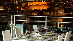 Mesa lista para cenar con vista a la ciudad de noche.