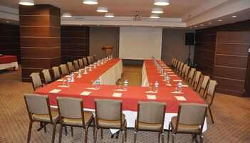 Un salón de conferencias con una larga mesa, sillas y una pantalla para proyector.