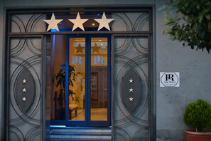 A hotel entrance with a glass door, decorative stars, and a sign with the initials "IR". - Hotel Rosignano (Rosignano Marittimo)