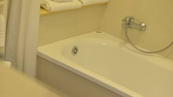 A bathroom with a bathtub, a shower, and a sink.