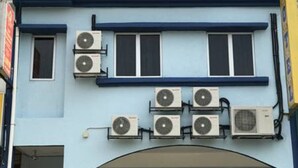 A hotel with a signboard displaying the name 'MAHA HOTEL' and contact numbers. There are multiple air conditioning units attached to the building's exterior. - Maha Hotel (Puchong)