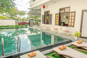 A swimming pool with lounge chairs and a small garden area. - Horizon 2 Villa Hoi An (Da Nang)