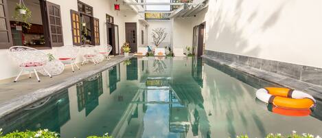 A pool area with lounge chairs and a lifebuoy, surrounded by greenery and a sign reading "Horizon 2 Villa".