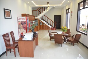 Amplia sala de estar con escalera de madera, una mesa de comedor con sillas y una estación de café.
