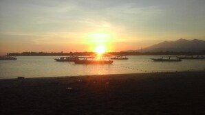 A sunset over a calm river with boats. - Padanta Homestay (Gili Trawangan)